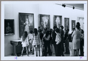 School children and docents in front of a wall of Darnall paintings at the Maryland Historical Society (now known as the Maryland Center for History and Culture) in Baltimore, Maryland. Shows paintings along the walls of the Thomas and Hugg Building, and a group of children listening to the explanation provided by the museum docent.