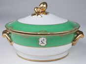 Covered entree dish or tureen featuring the McKim family crest on exterior of basin. The green and white lid has a gold fruit-shaped finial. The basin is green at the top and white at the bottom, with a thin gilt band separating the two colors. The rims and handles of the basin and lid are…