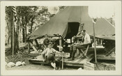 View of the Camp Hutzler headquarters, with W. E. Brill seated at right and three boys, possibly his sons, at center. Established by Albert and Joel Hutzler, of the Baltimore-based Hutzler's department store, the camp ran from 1921 to 1923. From July through September, employees of Hutzler's could go to the camp, located in the…