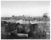 Looking north from the Federal Hill neighborhood across the Inner Harbor at downtown Baltimore, Maryland. The buildings in the immediate foreground lie north of Hughes Street, which would later become the western end of Key Highway. To the left steamships are moored at the Light Street wharves while the Pratt Street wharves, which had been…