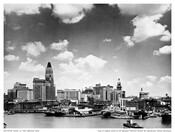 Looking north from the Federal Hill neighborhood at the Inner Harbor and downtown Baltimore, Maryland. Visible at center is the United Fruit Company's terminal located at Pratt Street Pier 1, whose vessels transported tropical fruit from the Caribbean to mainland United States ports. The tall spired building visible in the right background is the Hearst…