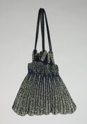 Knitted navy blue purse silk and cut steel bead bag featuring vertical flame design. Eight knitted and beaded loops attached at top of bag are carriers for twisted cord drawstring handles. Purse is unlined. Belonged to Mrs. Walter Penrose Summers (nee Grace Wootten Hubbard).