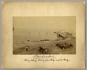 Three figures near a wharf on the Chesapeake Bay in Tolchester, Maryland. Two of the figures sit in a cart, while the other stands to the side. A ship can be seen sailing in the distance. Tolchester was the site of the Tolchester Beach Amusement Park, which consisted of a bathing beach, amusement park, racetrack,…