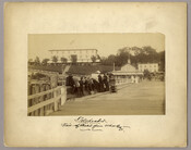 Approximately 10 figures standing on the edge of a wharf, looking over the railing in front of the hotel at Tolchester, Maryland. Tolchester was the site of the Tolchester Beach Amusement Park, which consisted of a bathing beach, amusement park, racetrack, and hotel, and was in operation from 1877 to 1962. The Kent County park…
