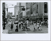 View of pedestrians and cars at the intersection of North Howard and West Lexington Streets in Baltimore, Maryland. The Read's Drug Store located at 123 North Howard Street is visible at right.