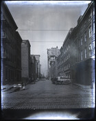 View of South Calvert Street looking north from East Pratt Street in Baltimore, Maryland. A peanut vendor, cobblestone street, and streetcar tracks are visible.