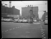 Street view of a parking lot full of cars at the intersection of South Paca Street and Camden Street in Baltimore, Maryland. Shows row houses and warehouse in background.