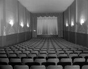 The interior of an empty theater showing the stage and rows of seats.