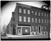 McCulloh Delicatessen storefront visible from the street. The store was located at the corner of McCulloh Street and Wilson Street in Baltimore, Maryland. A street sign is partially visible to the far right.