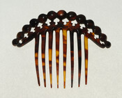 Carved hair comb with eight prongs and beaded top.