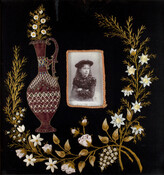 Embroidered needlework picture with applied cabinet card of Ethel Russell on black velvet ground. Embroidery in the form of an applied maroon urn on the left with the cabinet card in the center, surrounded by silk embroidered leaves and ribbon work flowers.